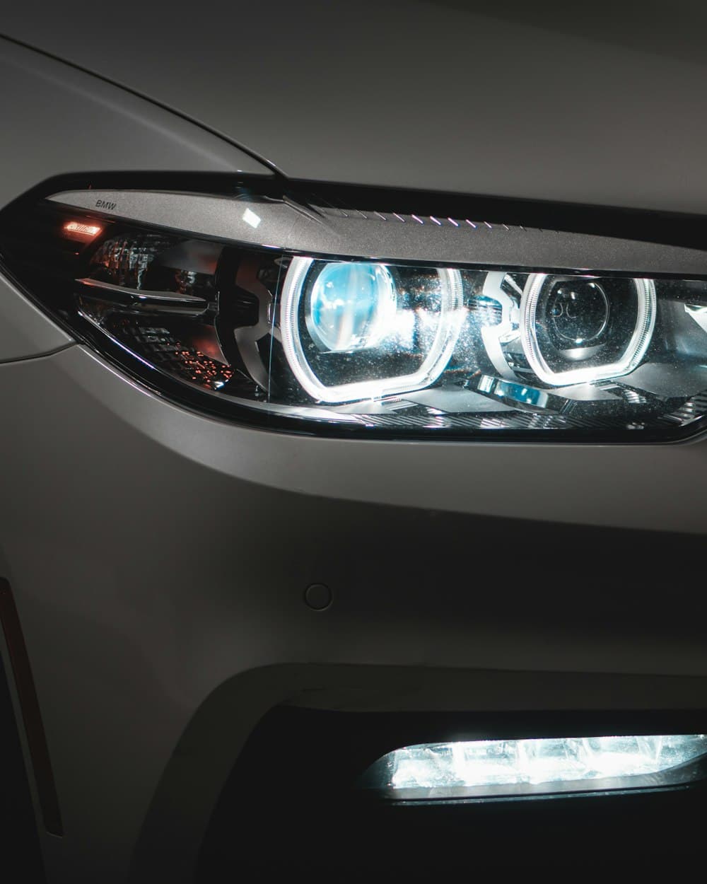 An LED headlight and daytime running light on a grey car