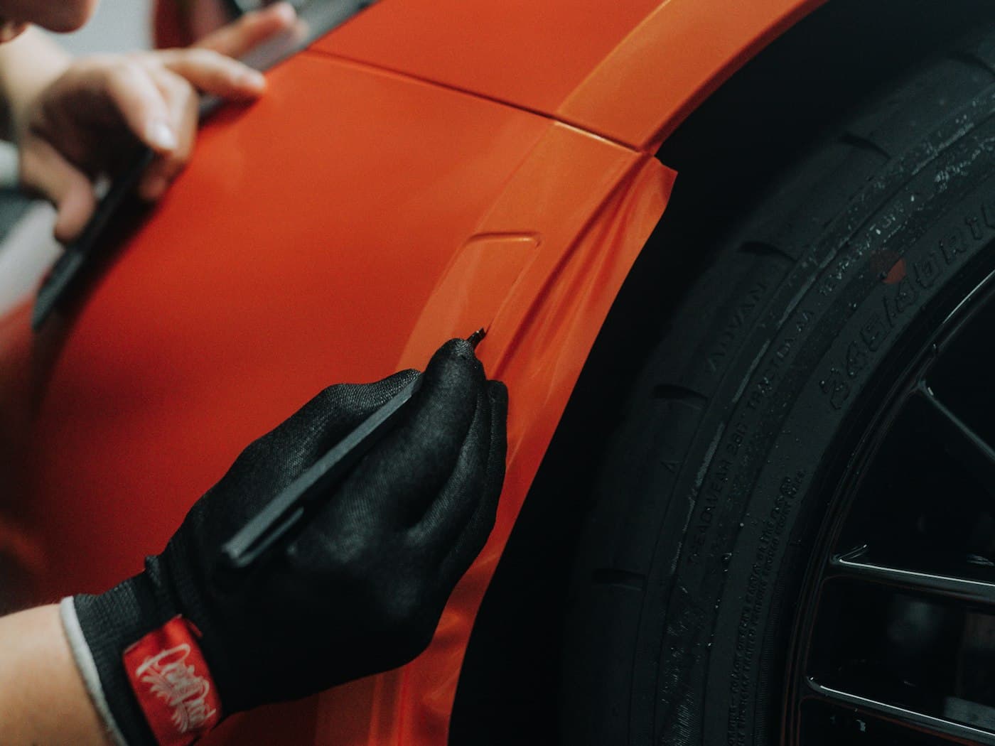 Orange vinyl wrap being smoothed onto a wing