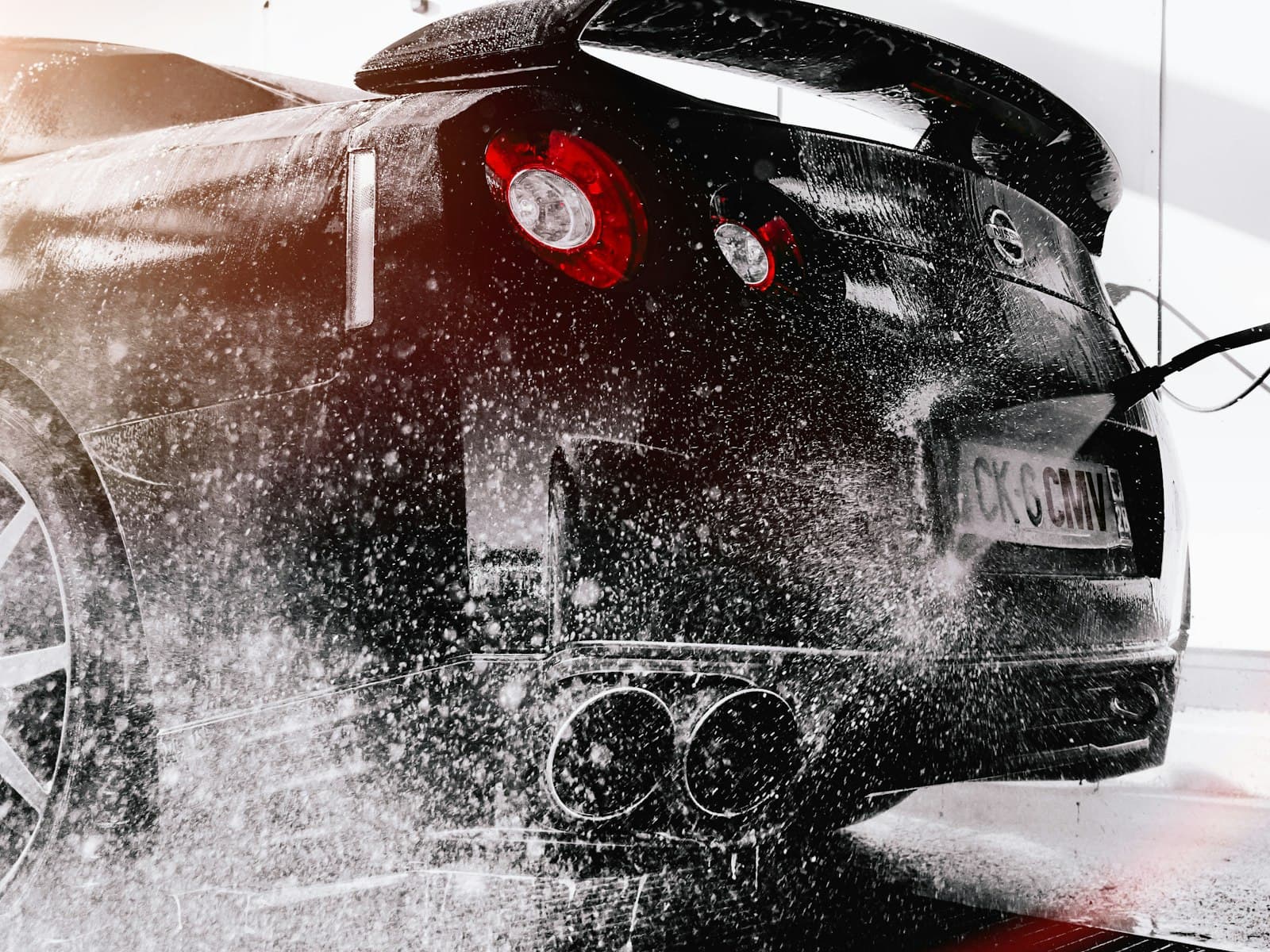 Foam being rinsed from the rear of a dark car